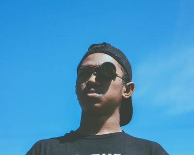 在蓝天下戴着黑色帽子和望远镜的男子