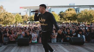 一名身穿黑色长袖衬衫的男子在台上的人群面前手持麦克风