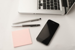 将灰色Iphone 6放在两支可伸缩笔和Macbook旁边