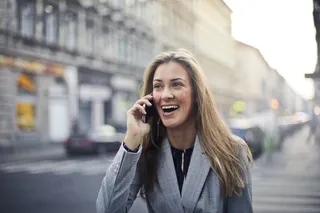 金发女人穿着灰色西装外套手持智能手机