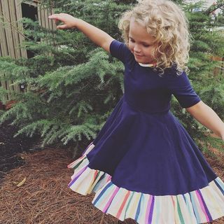 在绿叶植物附近，女孩穿着半袖连衣裙的照片