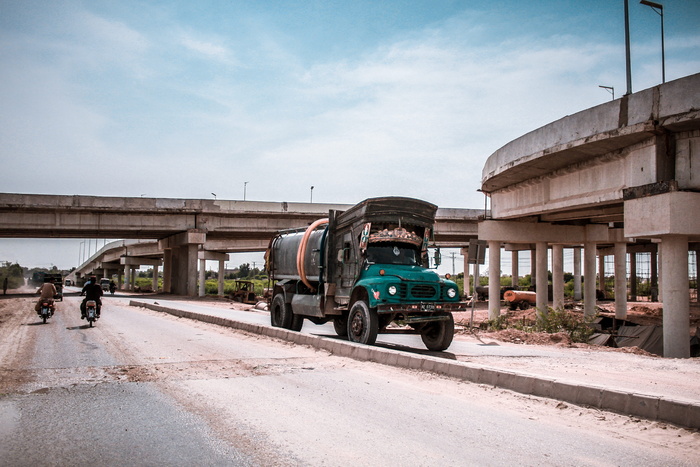 大楼附近的道路上有一辆蓝色和黑色卡车，还有两辆摩托车