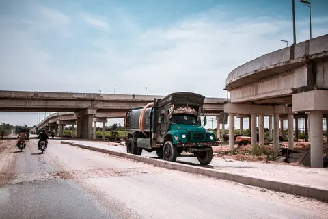 大楼附近的道路上有一辆蓝色和黑色卡车,还有两辆摩托车 大楼附近的道路上有一辆蓝色和黑色卡车,还有两辆摩托车