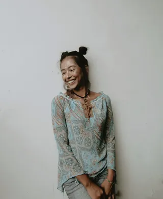 面带微笑的女人，穿着蓝色上衣，靠在墙上