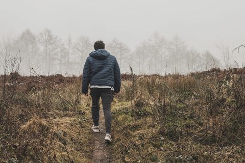 身穿蓝色泡泡连帽衫夹克的男子在绿色草地上行走 身穿蓝色泡泡连帽衫夹克的男子在绿色草地上行走