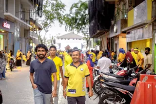 两个男人微笑着走着，周围都是人