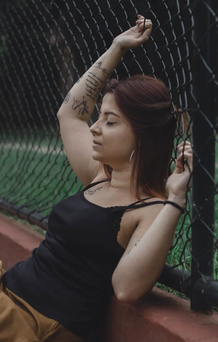 靠在黑色旋风栅栏上的女人