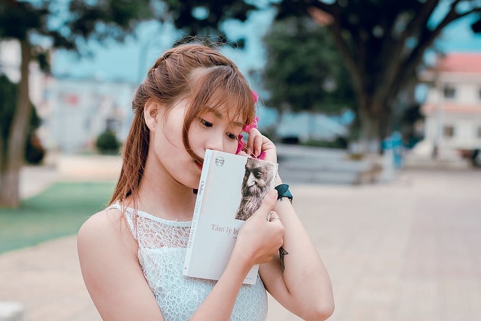 穿着白色蕾丝上衣拿着书的女人
