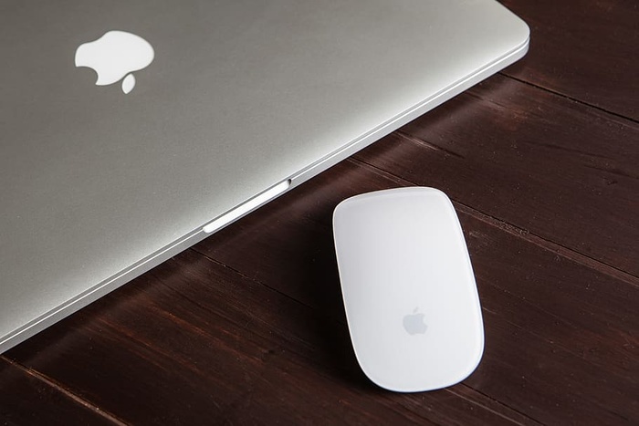 一张Macbook Pro和魔法鼠标放在木桌上的特写镜头，图像是用佳能5D单反相机拍摄的