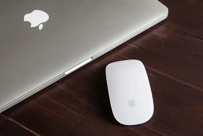 一张Macbook Pro和魔法鼠标放在木桌上的特写镜头，图像是用佳能5D单反相机拍摄的