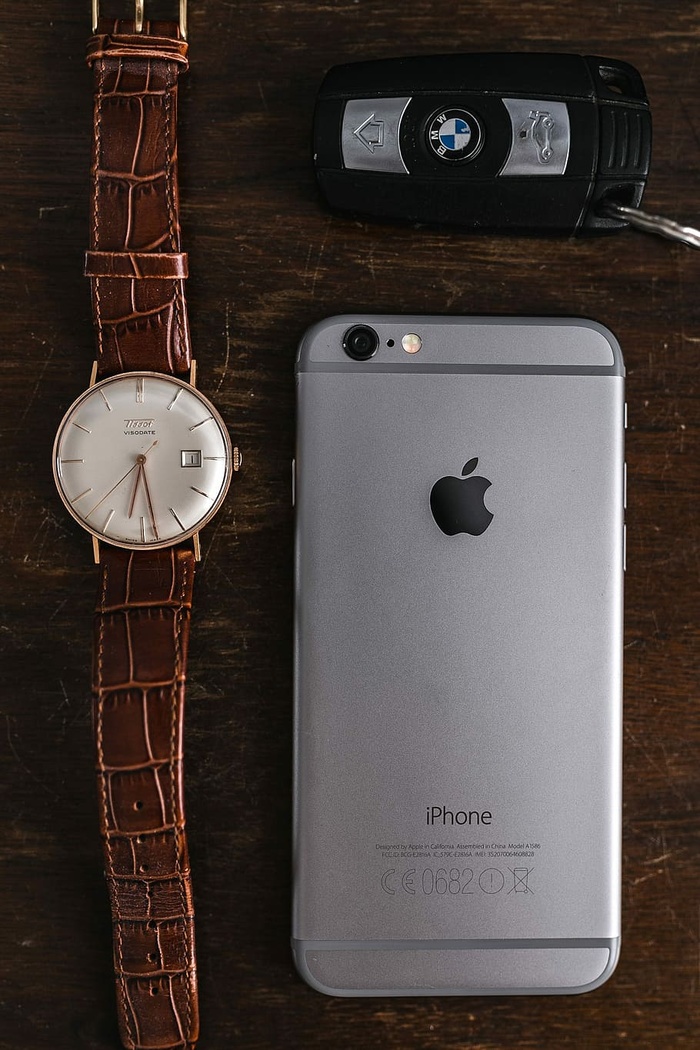 棕色皮夹上的苹果iPhone 6和复古手表