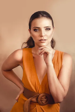 身着芥末装的女子手放在下巴上摆姿势的照片