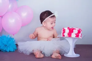 蛋糕旁穿着白色短裙的婴儿
