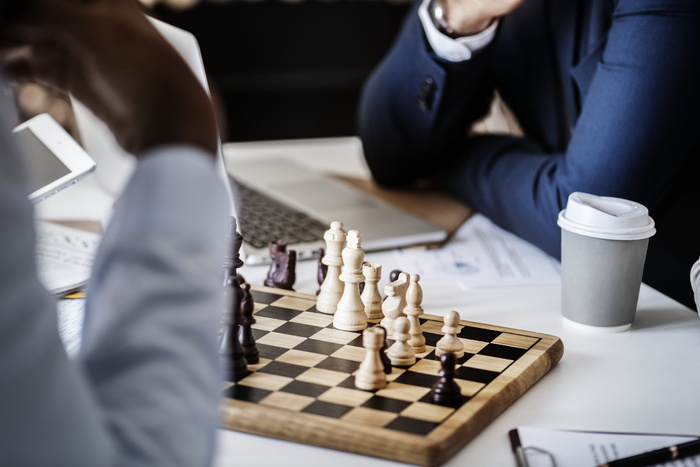 白色和灰色一次性杯子旁边的桌子上摆着棕色木制象棋的照片