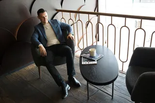 坐在棕色金属栏杆旁沙发椅上的男子