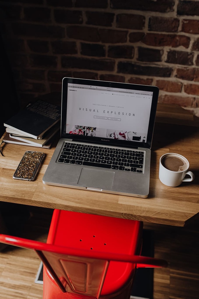 Creatives办公桌，砖墙前有笔记本电脑、相机、日记和书籍