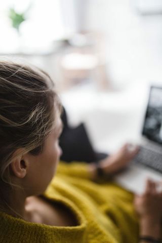 坐在沙发上用笔记本电脑工作的年轻女子