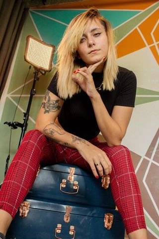 照片中，一名女子坐在蓝色行李箱上，同时托住下巴