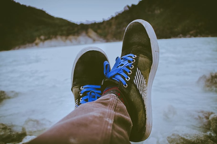 在水体前穿着黑色和棕色鞋子的人