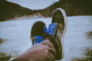 在水体前穿着黑色和棕色鞋子的人