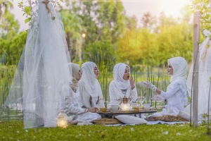 4名身穿白色阿巴亚婚纱的女性在树旁野餐