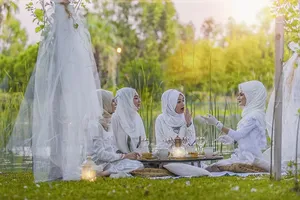 4名身穿白色阿巴亚婚纱的女性在树旁野餐