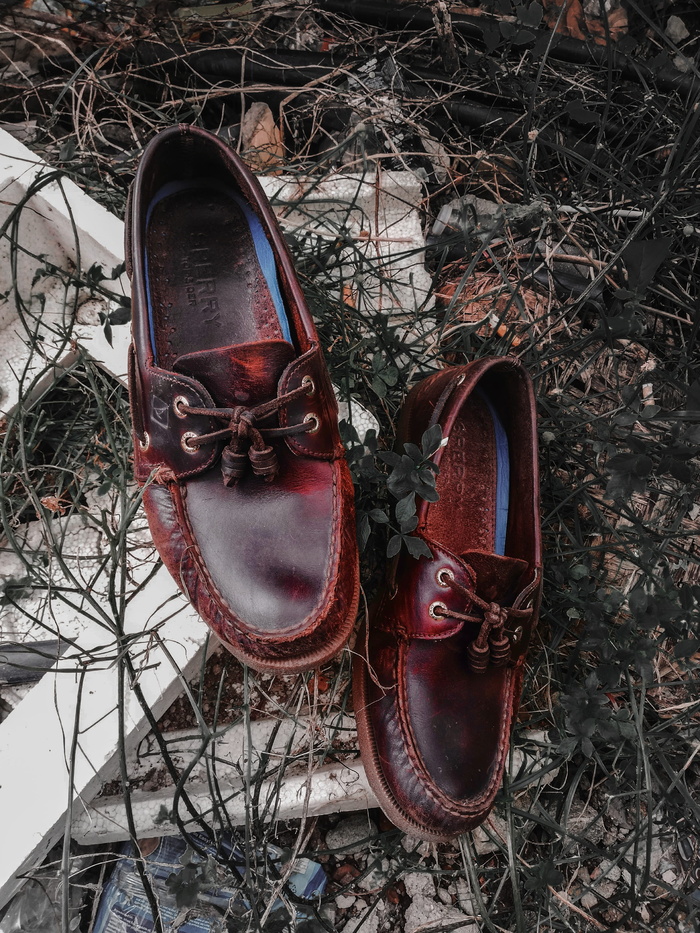 白色木板上的一双棕色Sperry皮船鞋