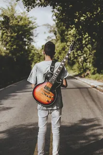 拿着棕色和黑色Les Paul电吉他的男子