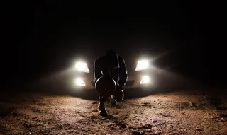 男子靠在前照灯上蹲着拿球