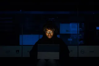 身穿黑色连帽衫夹克、手持灰色笔记本电脑的女子