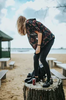 美丽的金发女人在海滩边的树桩上拿着一罐可乐放松 美丽的金发女人在海滩边的树桩上拿着一罐可乐放松