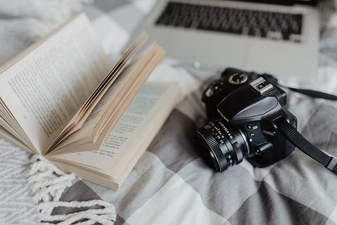 一台相机、MacBook和一本书在床上等着