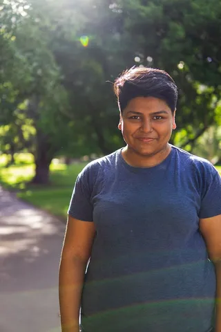 一名女子站在树旁街道上的照片