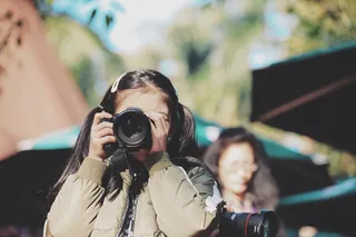 脸上拿着单反相机的女孩