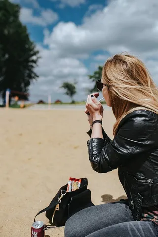 在海滩上穿着皮夹克和墨镜的年轻女子