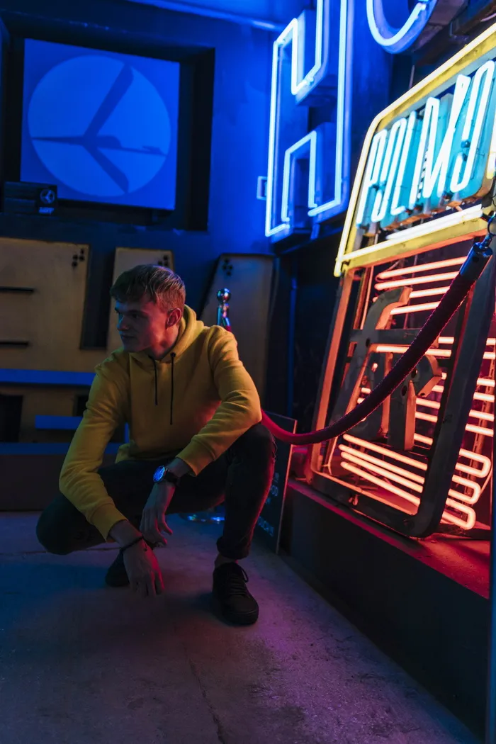 男子蹲在霓虹灯旁的照片