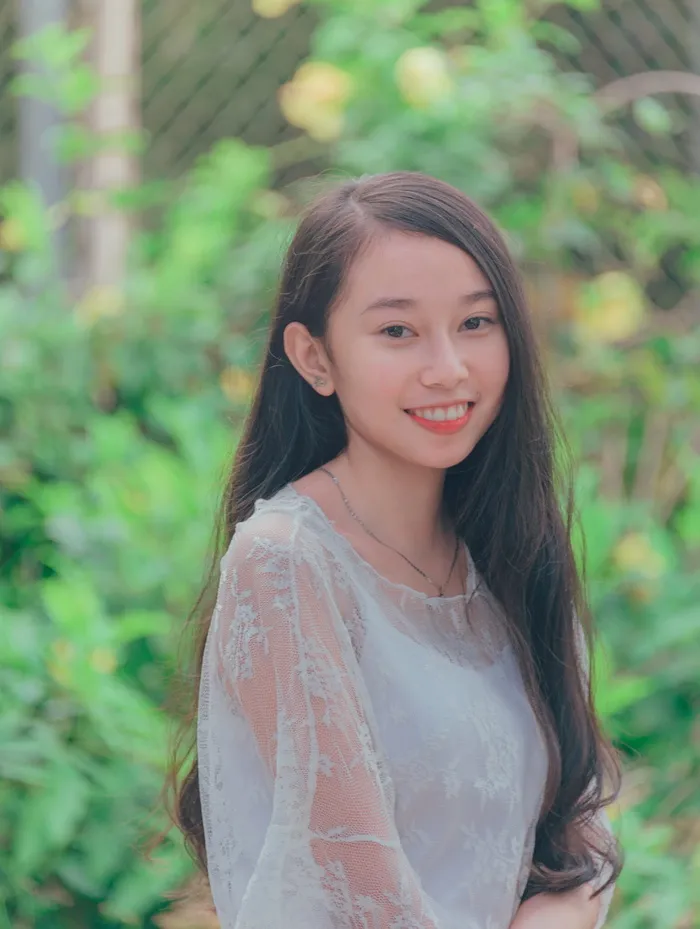 女人穿着白色背心与绿叶植物拍照
