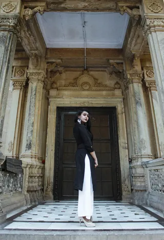 站着的女人，穿着黑色长袖衬衫和白色裤子