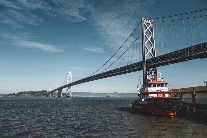 boat on body of water under suspension bridge