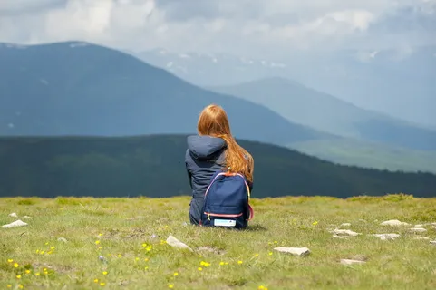 穿着灰色连帽夹克坐在草地上的人