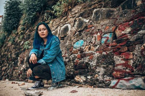 坐在棕色混凝土墙旁边的女人