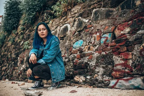 坐在棕色混凝土墙旁边的女人 坐在棕色混凝土墙旁边的女人