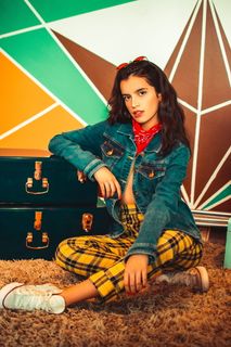 坐在地板上靠着蓝色行李箱的女人的照片