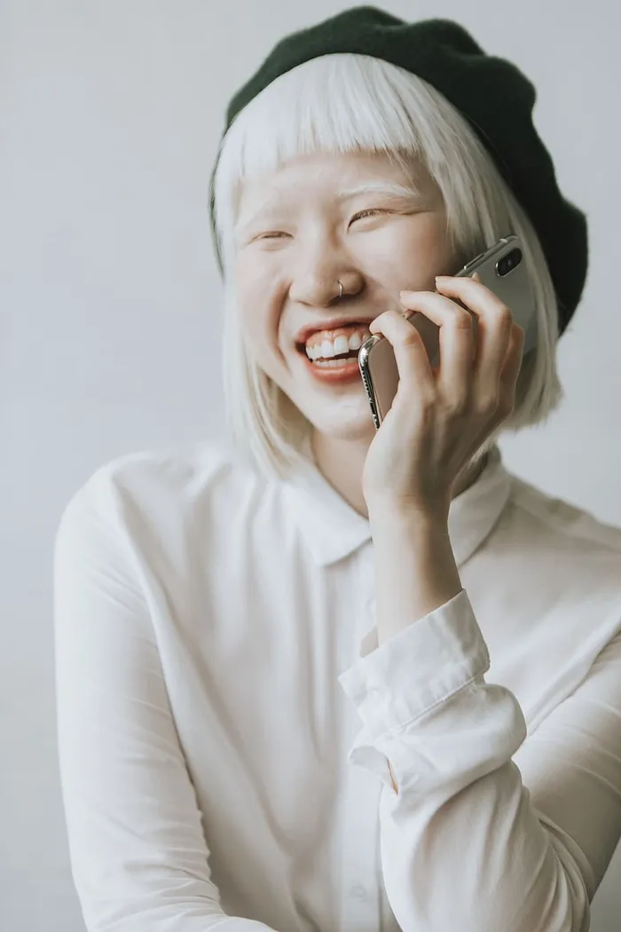 身穿白色纽扣长袖衬衫、手持Iphone X的女子