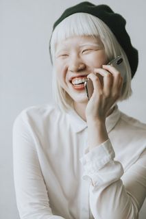 身穿白色纽扣长袖衬衫、手持Iphone X的女子