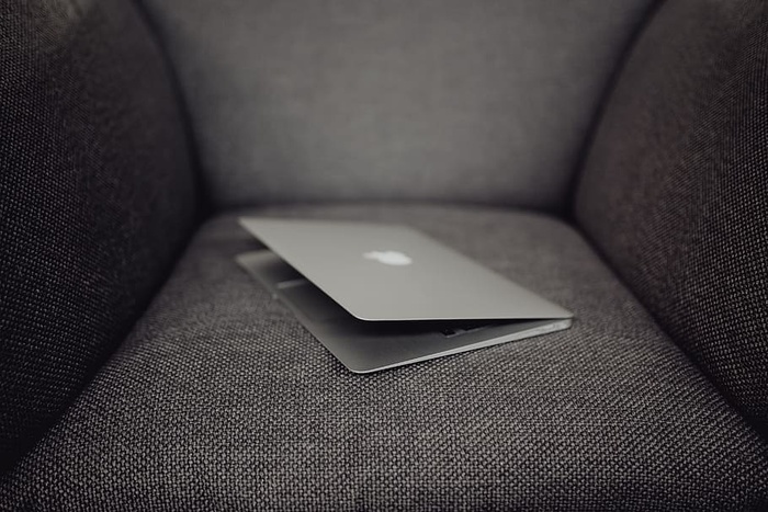 关闭的笔记本电脑躺在灰色扶手椅上的特写镜头