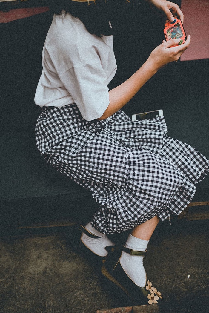 女孩坐在沙发上玩便携式控制台的特写照片