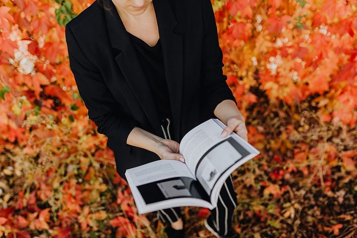 以五颜六色的树叶为背景，拿着格拉夫康夫书的女孩