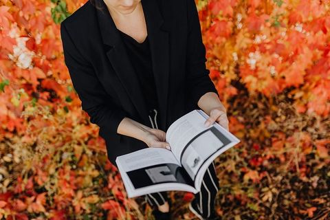 以五颜六色的树叶为背景，拿着格拉夫康夫书的女孩