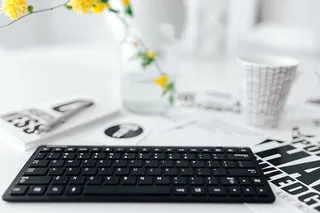 女性用手在远程无线电脑键盘上打字